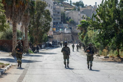 Des soldats israéliens patrouillent dans une rue de Qusra, en Cisjordanie occupée, où des colons israéliens assiègent des maisons palestiniennes, le 13 août 2026 — Zain JAAFAR / AFP
