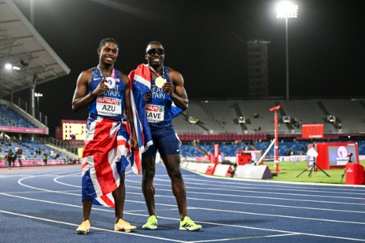 Les Britanniques Jeremiah Azu (g) et Romell Glave fêtent leurs médailles d'argent et d'or respectivement du 100m des championnats d'Europe devant les tribunes dégarnies de l'Alexander Stadium de Birmingham, le 11 août 2026 — Paul ELLIS / AFP