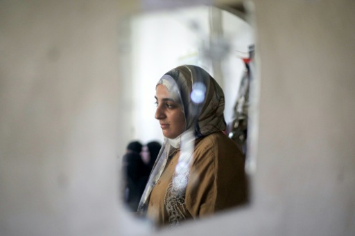 Saba Rabah, meilleure élève palestinienne aux examens de second cycle, en filière scientifique, se tient devant un miroir brisé sur un mur du camp de réfugiés de Maghazi, au centre de la bande de Gaza, le 26 juillet 2026 — Eyad Baba / AFP