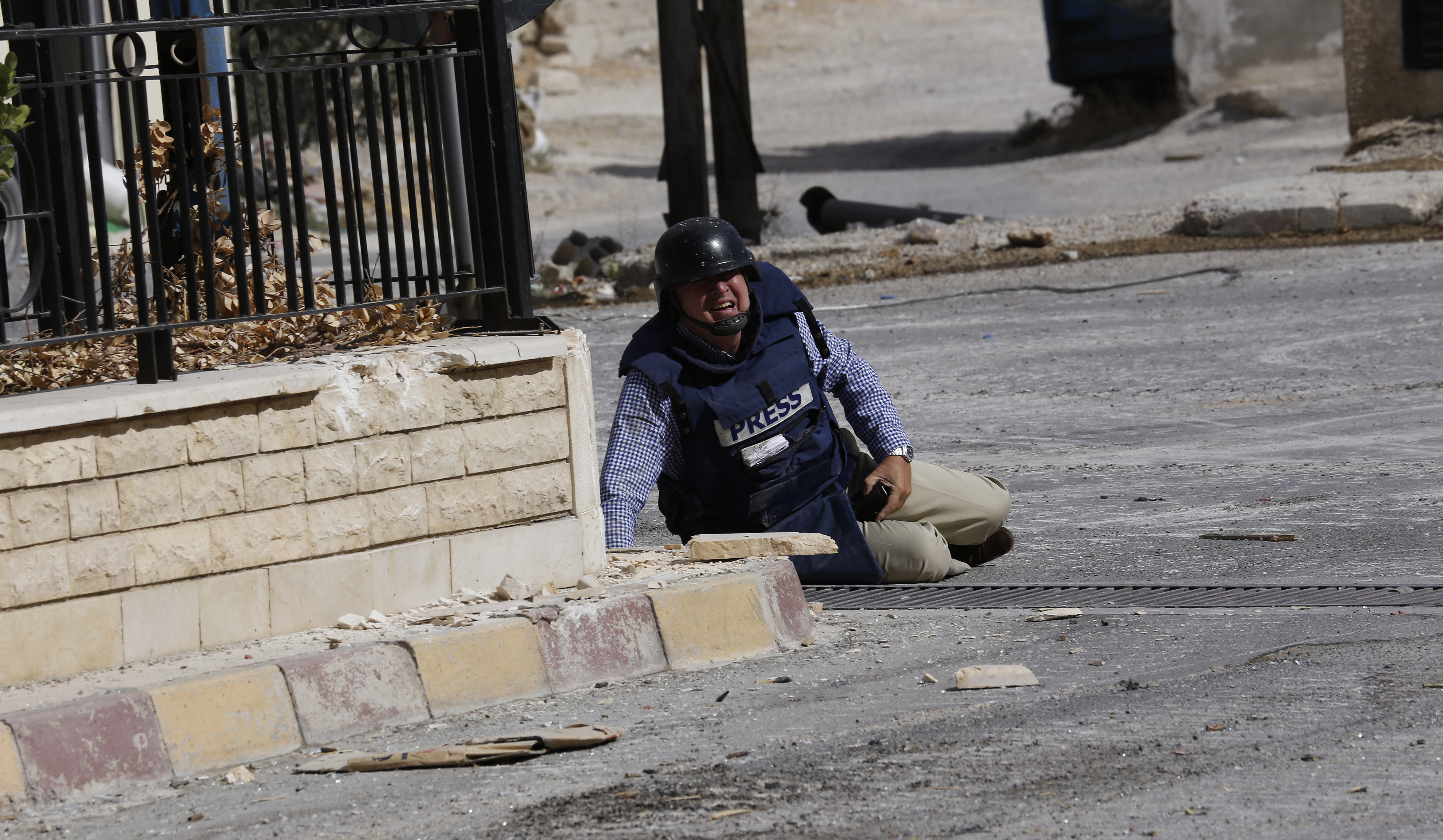 AFP reporter Sammy Ketz lies on the ground during sniper fire in the ancient Christian Syrian town of Maalula, on September 18, 2013