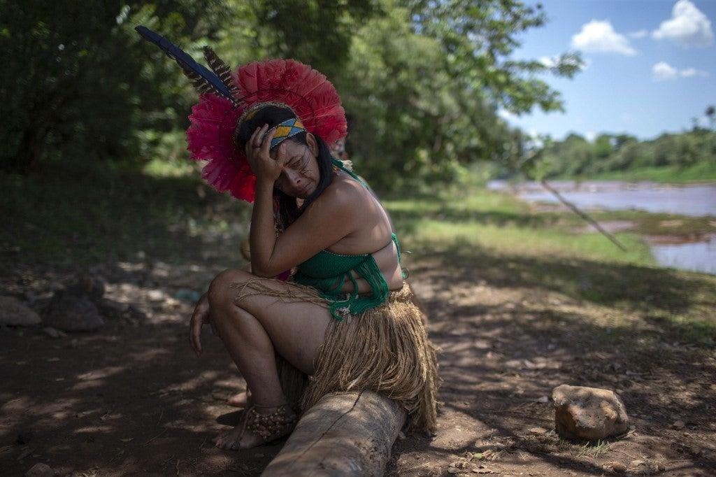 Une femme indigène de la communauté Pataxós Ha-ha-hae pleure en regardant la rivière Paraopeba couverte de boue, le sixième jour après l'effondrement d'un barrage dans une mine de fer près de la ville de Brumadinho. Mauro Pimentel/AFP