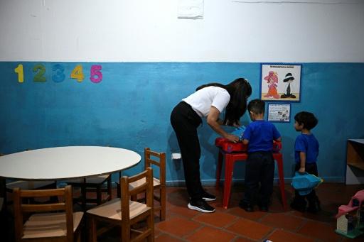 Une enseignante joue avec deux enfants dans une école de La Guaira, le 15 septembre 2026, au nord du Venezuela. — Federico Parra / AFP