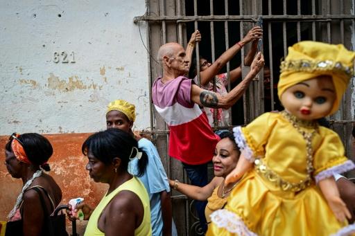 Un hombre con un tatuaje del guerrillero argentino Ernesto 'Che' Guevara toma una fotografía con su móvil mientras los devotos de la Virgen de la Caridad del Cobre —identificada como Oshún en la religión yoruba, de origen africano— participan en una procesión durante las celebraciones por el día de la patrona de Cuba en La Habana, el 8 de septiembre de 2026 — YAMIL LAGE / AFP