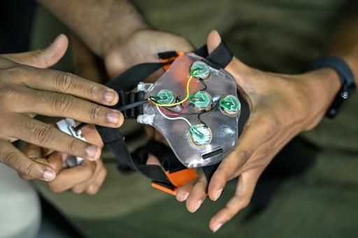 Akash Kulgod (d), cofondateur de Dognosis, tient un dispositif d'interface cerveau-machine (ICM), le 28 juillet 2026 à Kempohalli, en périphérie de Bangalore, en Inde — Idrees MOHAMMED / AFP