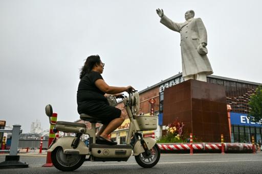 Una mujer pasa en moto frente a una estatua de Mao Zedong en la ciudad china de Shijiazhuang, en el norte de China — Pedro PARDO / AFP