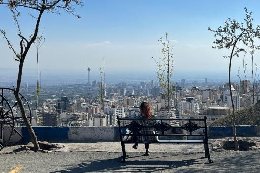 Une femme assise sur un banc au parc Pardisan, surplombant Téhéran, le 22 avril 2026 en Iran — - / AFP