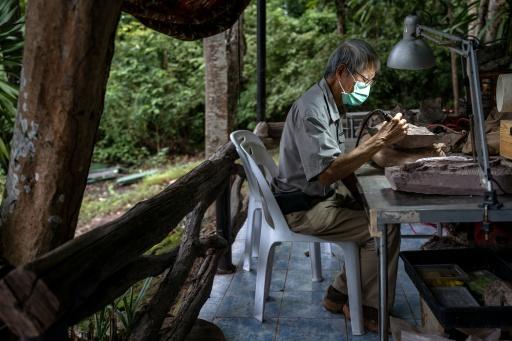 Le paléontologue Varavudh Suteethorn nettoie la terre entourant des morceaux de fossile de dinosaure dans le parc national de Phu Wiang à Khon Kaen, en Thaïlande, le 19 août 2026 — Chanakarn LAOSARAKHAM / AFP