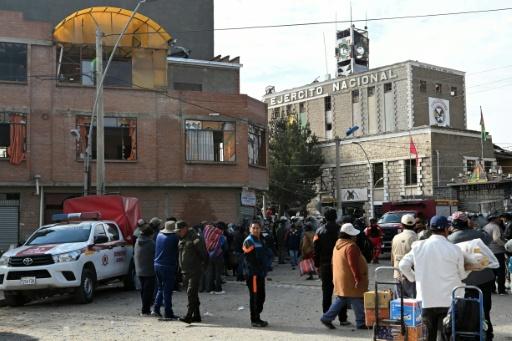 Residents stand outside a building with shattered windows following an explosion at a nearby army base in Viacha, Bolivia — AIZAR RALDES / AFP