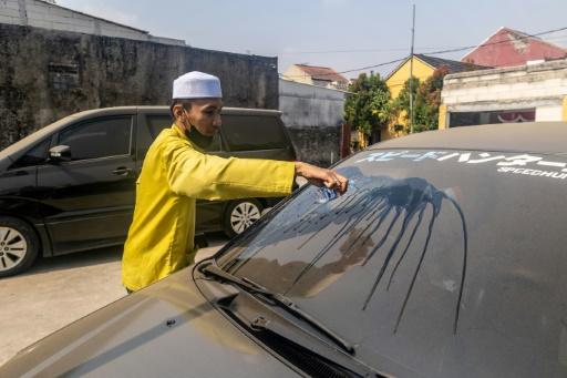 Un homme nettoie le pare-brise de sa voiture pour en retirer les cendres volcaniques après l'éruption du mont Anak Krakatoa à Bogor, dans la province de Java occidental, en Indonésie, le 6 septembre 2026 — ADITYA Aji / AFP
