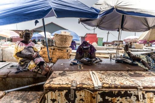 Fishmongers rest on top of their ice boxes at the fish landing in the town of Tanji, where ice is increasingly rare — MUHAMADOU BITTAYE / AFP