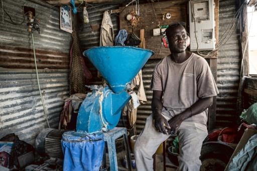 Amadou Gaye, 40, cannot run his millet milling machine without power at his shop in Sukuta — MUHAMADOU BITTAYE / AFP