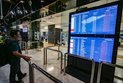 A stranded passenger looks at the departure board for the status of flights at Soekarno-Hatta Airport in Tangerang — Syarief Akbar / AFP