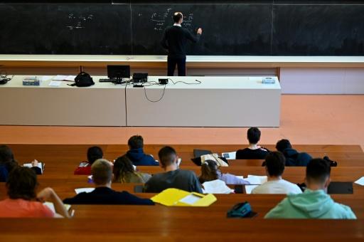 University of Rennes 1 students, wearing protective nose and mouth masks to curb the spread of the novel coronavirus, Covid-19, sit in an auditorium as they attend a supervised physics lecture in Rennes, western France on January 4, 2021. — Damien MEYER / AFP