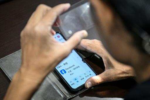 An elderly man uses a magnifier during a class on how to navigate AI-powered applications — Jade GAO / AFP